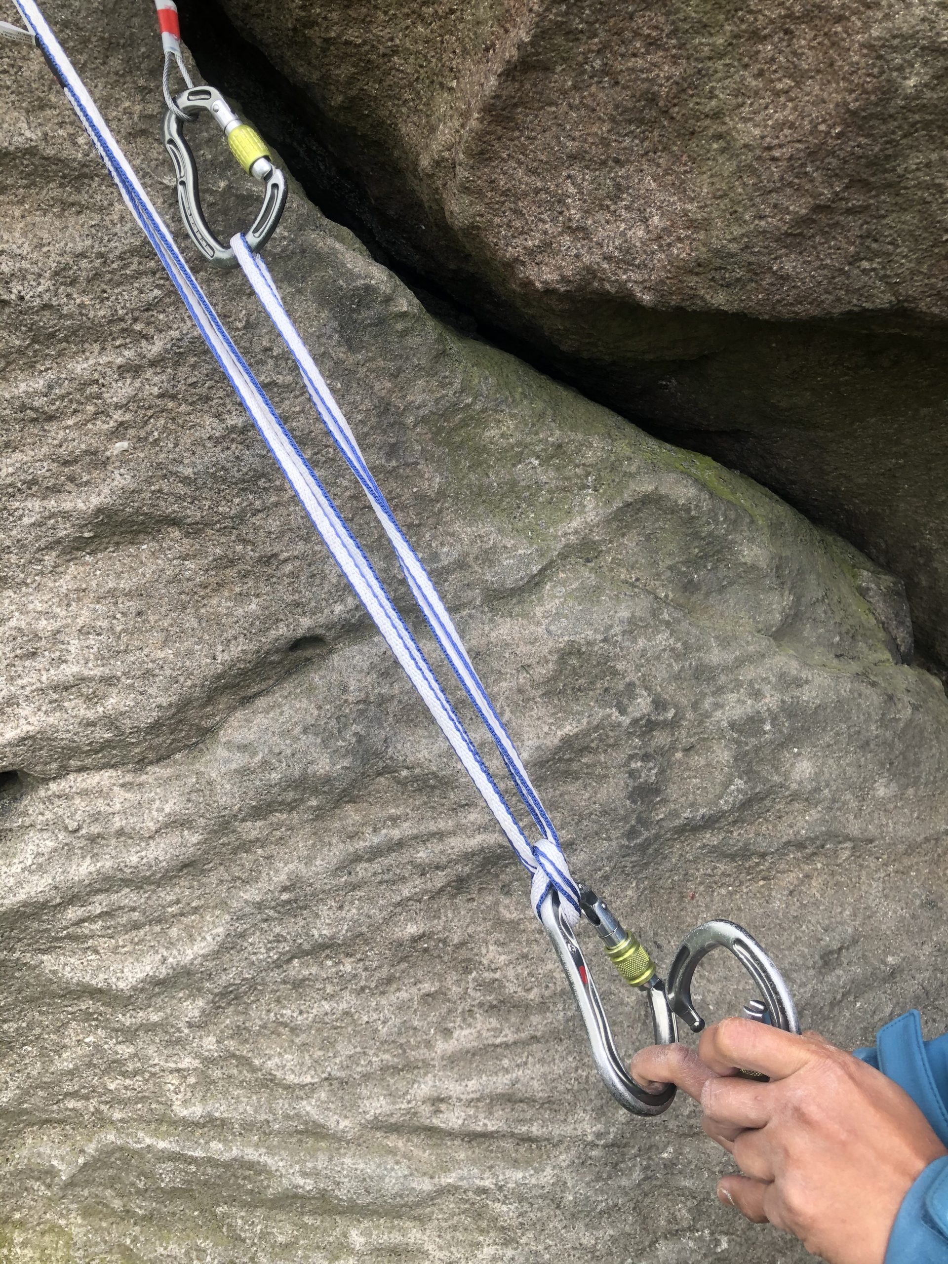 A method of attaching a climbing sling to two anchor points and then equalising the tension on both sides by using a clove hitch and karabiner to form a central power point ” width=