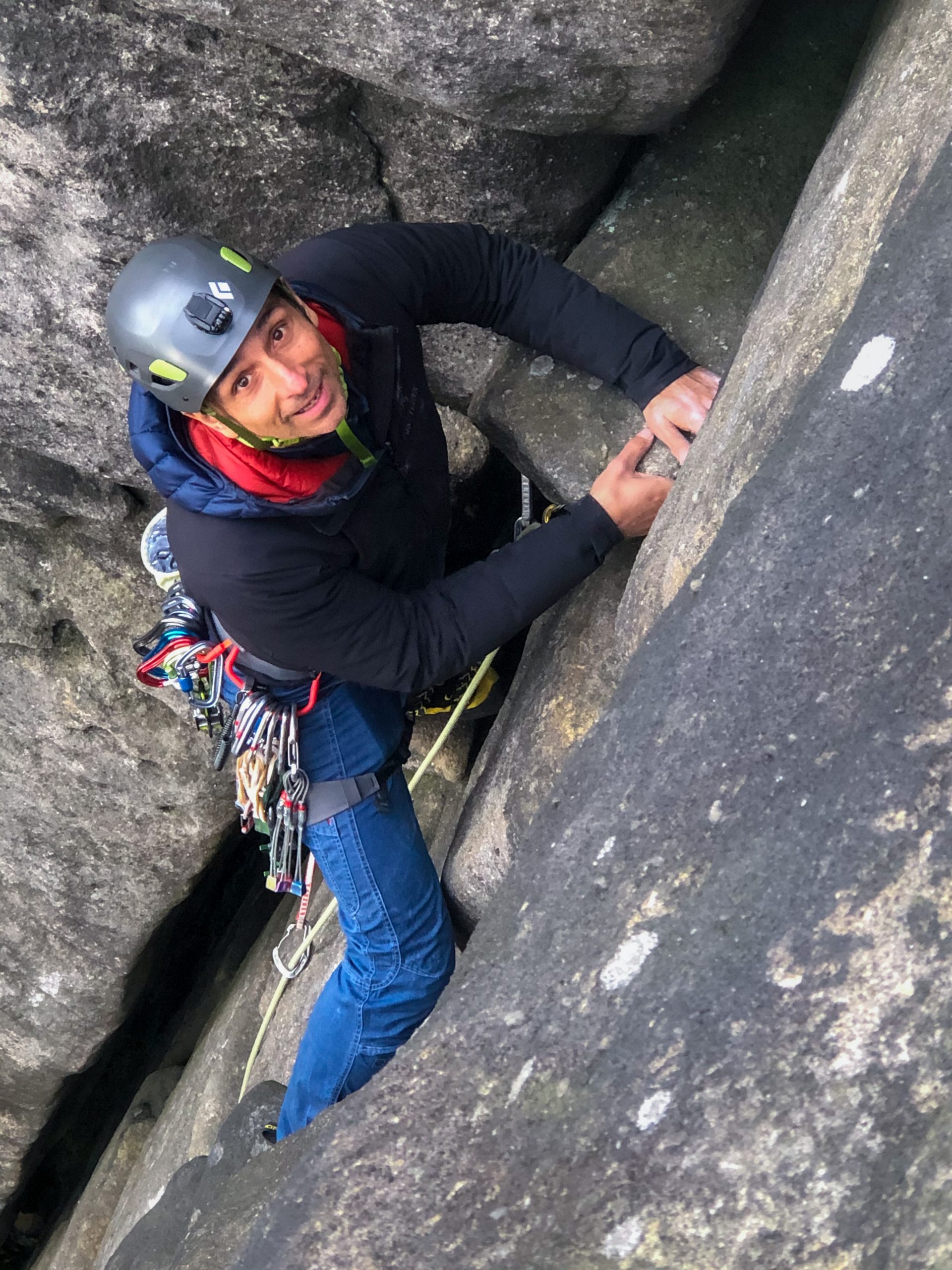 A climber smiles nervously as he learns to lead rock climb during a course in the Peak District