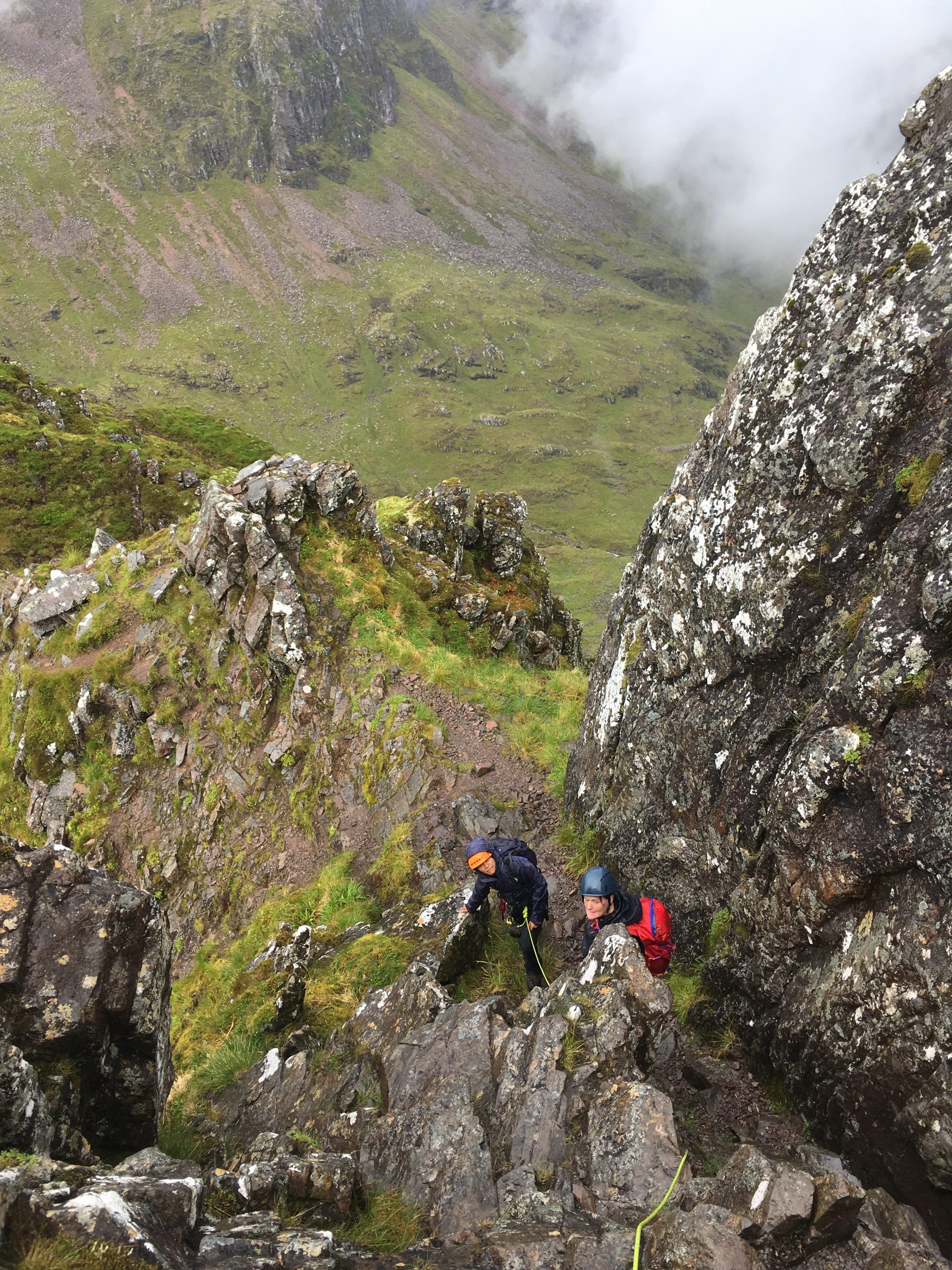 Two climbers wait their turn to move at one of the steeper sections while scrambling the Aonach Eagach Ridge in Glencoe