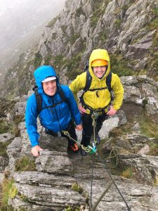 Two climbers smiling despite the rain while climbing Bastow Buttress on Tryfan during an advanced scrambling course