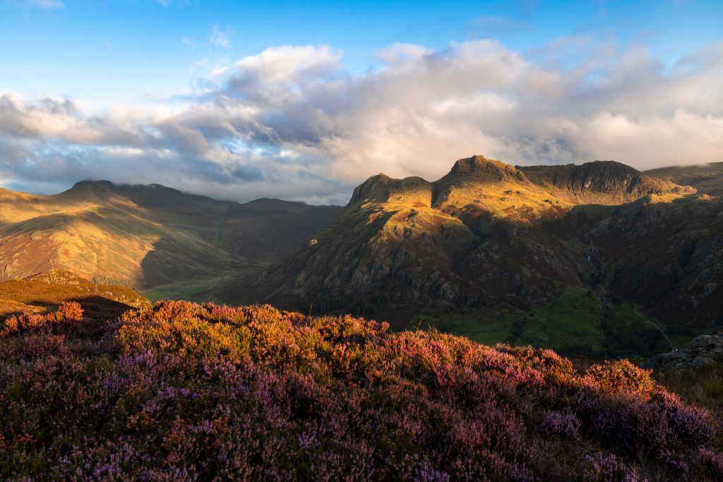 The first rays of the sunlight hit the Langdale Pikes during a guided mountain walk in the Lake District