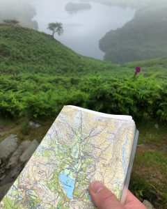 A map being orientated to match the features around it, in this case Grasmere, during a map reading course in the Lake District
