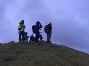 A group of walkers stand at the tope of a hill as the light is fading at the start of a night navigation course in Yorkshire