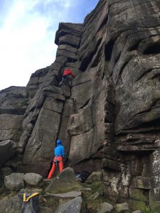 Two climbers climbing the crags at Stanage Edge in the Peak District during a rock climbing course