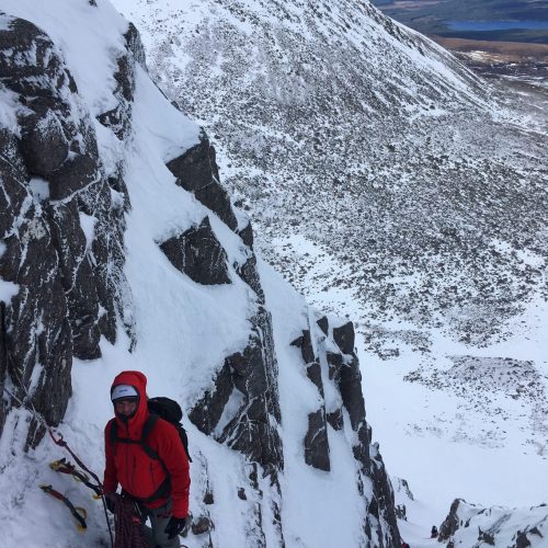 A climber waits at the belay stance of The Runnel in the Cairngorms during a winter climbing course