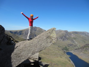 A scrambler stands confidently arms-outstretched on The Cannon on the North Ridge of Tryfan during a scrambling course