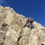 A mountaineer looks for the best route high up on a rock face while he learns to lead scrambles using a rope on this scrambling course in the Lake District