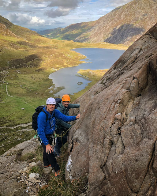 Two climbers belayed on a large ledge above Llyn Idwal during an advanced scrambling course in Snowdonia