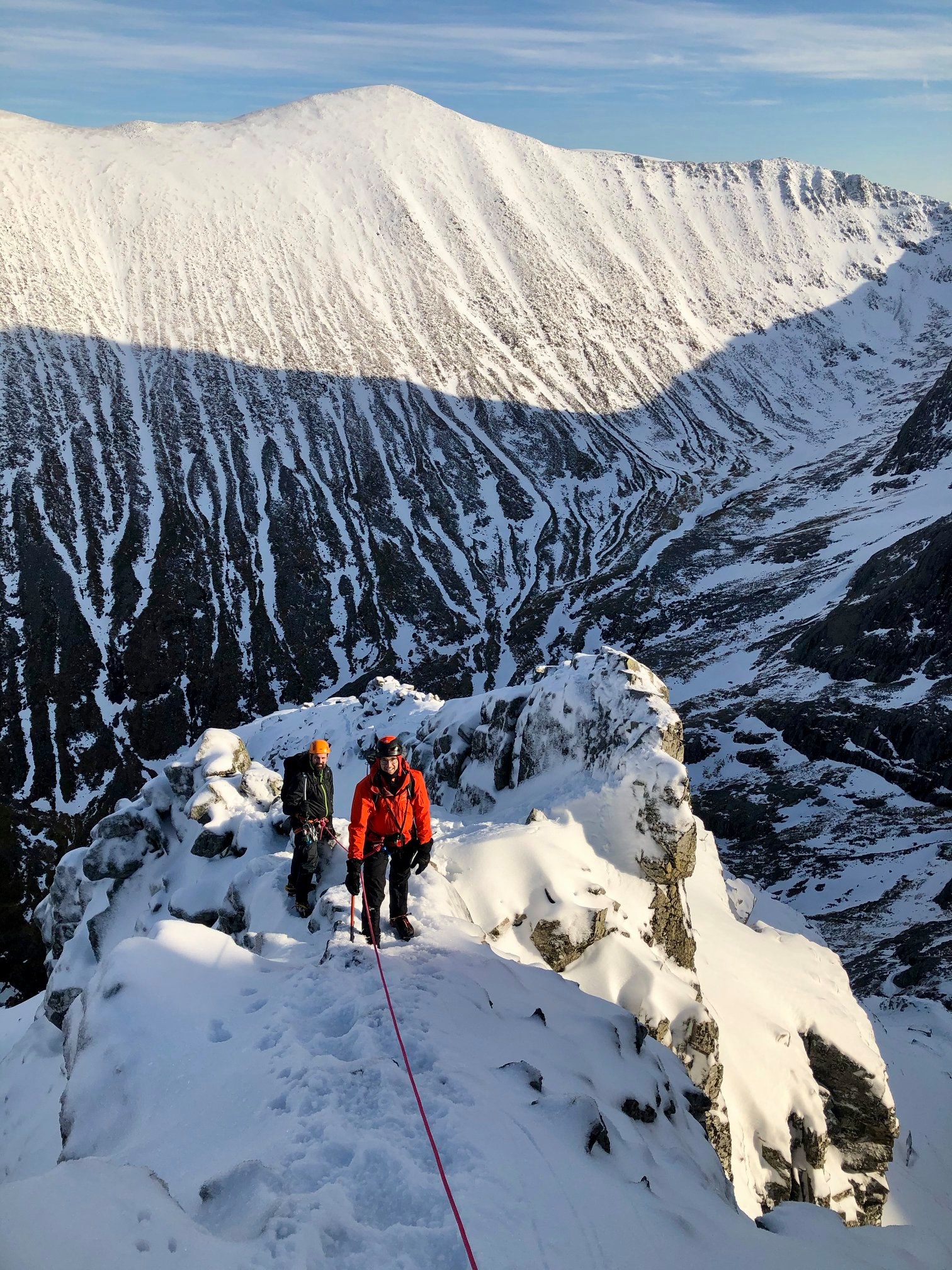 Two climbers are caught in a patch of sunlight as they make their way up Ledge Route, on Ben Nevis, which is covered in deep snow