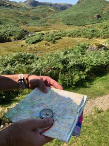 A person orientating their map using a compass to find north, during a map reading course in the Lake District