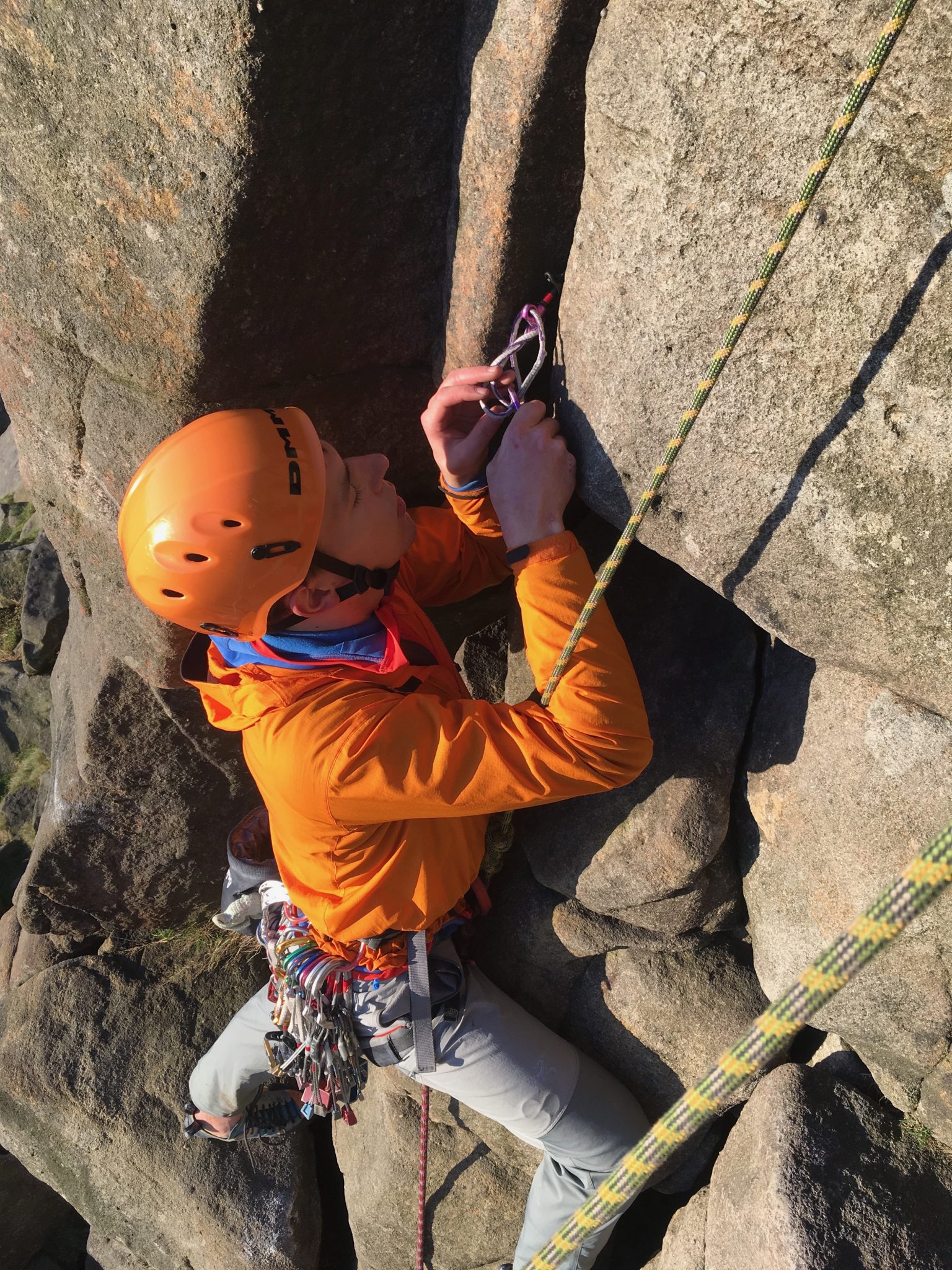 A rock climber removes equipment during a rock climbing course in the Peak District