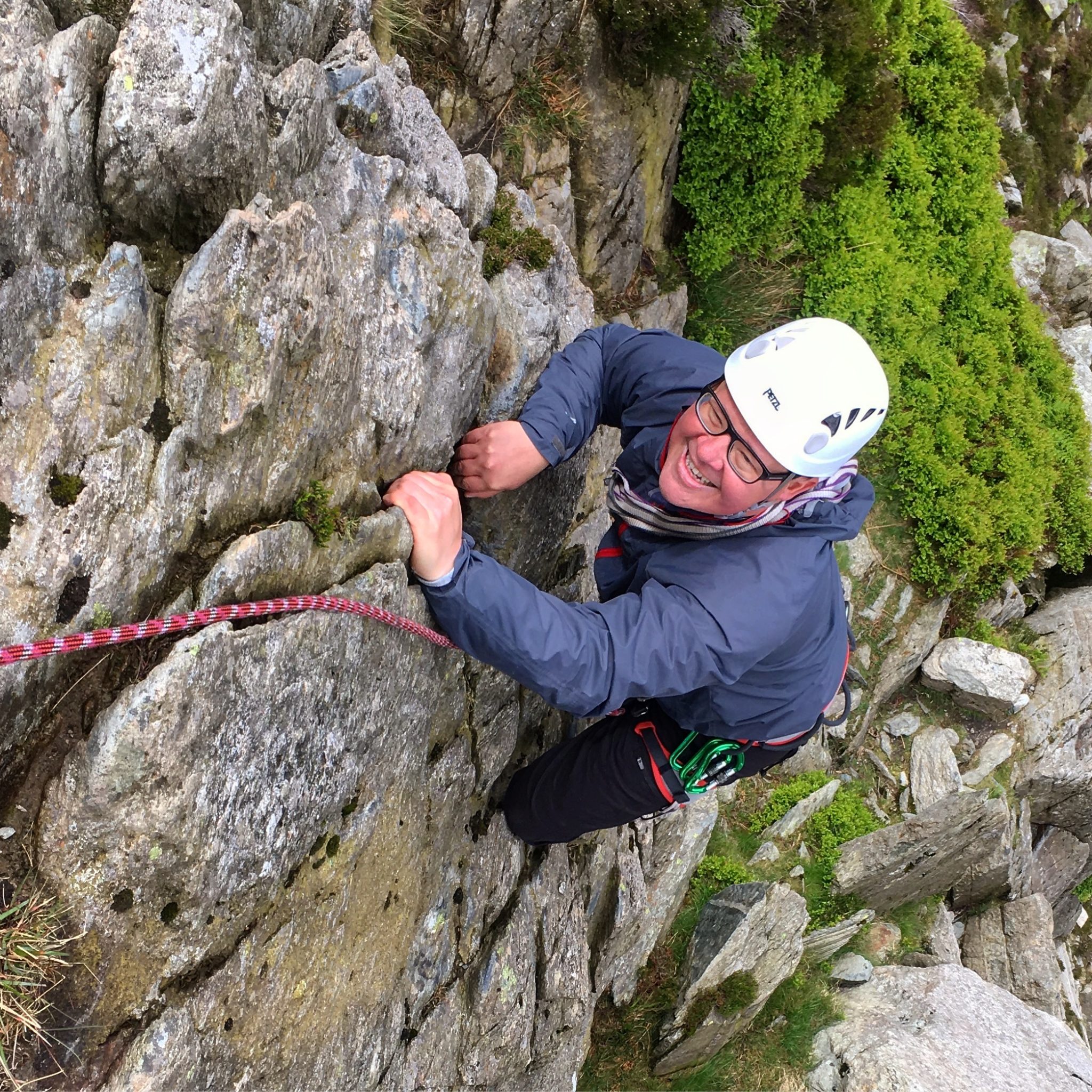 A climber grins as he makes a tricky move during a rock climbing course in Snowdonia