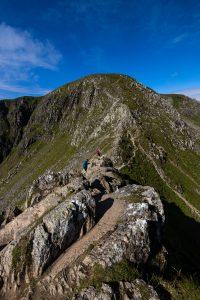 The headwall of Helvellyn looms up at the end of Striding Edge during a guided walk in the Lake District
