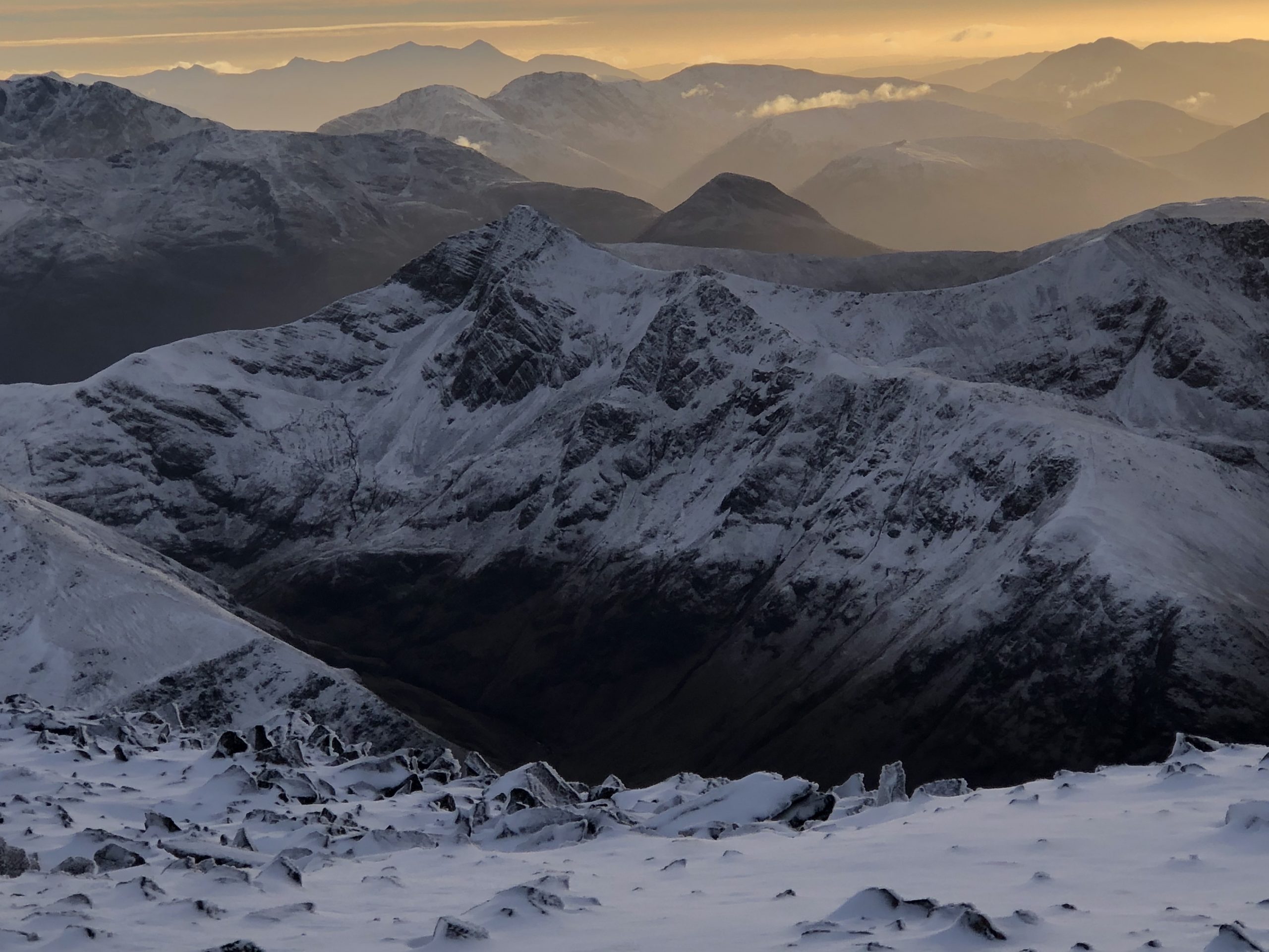 Looking south from Ben Nevis in winter as the sun sets - a view of the Mamores and beyond