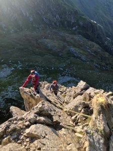 Climbers on the thin ridge section of the Cneifion Arete, a Grade 3 scramble in Snowdonia