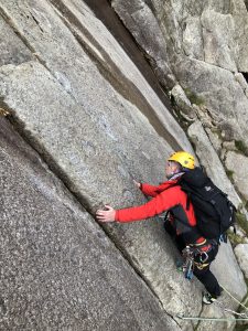 A climber working out his next move on the famous 'Twin Cracks' on Hope, a rock climb on Idwal Slabs during a multi-pitch climbing course in Snowdonia