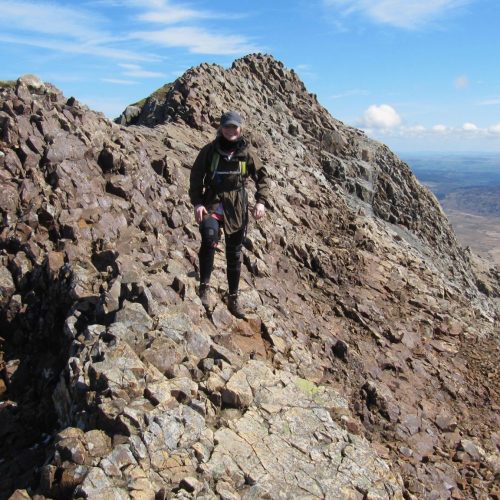A scrambler enjoying the good weather and views as she makes her way along Crib Goch on Snowdon during a guided scrambling day