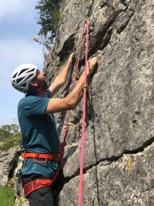 A rock climber climbing limestone sports routes in Yorkshire during a sports climbing course