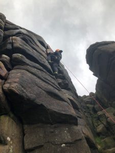 A climber being top roped on Heaven Crack at Stanage Edge in the Peak District during a rock climbing course